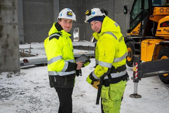 Prosjektingeniør Adrian Masvik og formann Daniel Romsdal i Kivijervi Entreprenør studerer 3D-modellen av anlegget på nettbrettet, der den daglige framgangen og endringer kan spores og studeres umiddelbart.